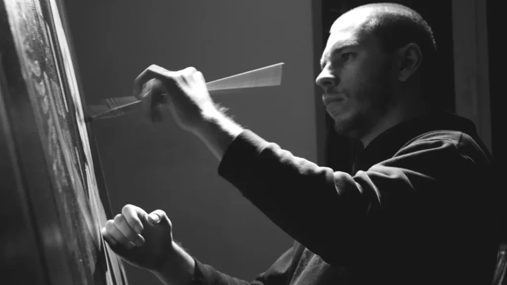 Black-white photo of an artist at a canvas holding a paintbrush