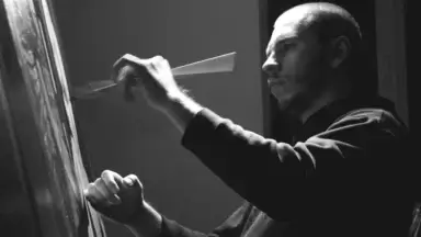 Black-white photo of an artist at a canvas holding a paintbrush